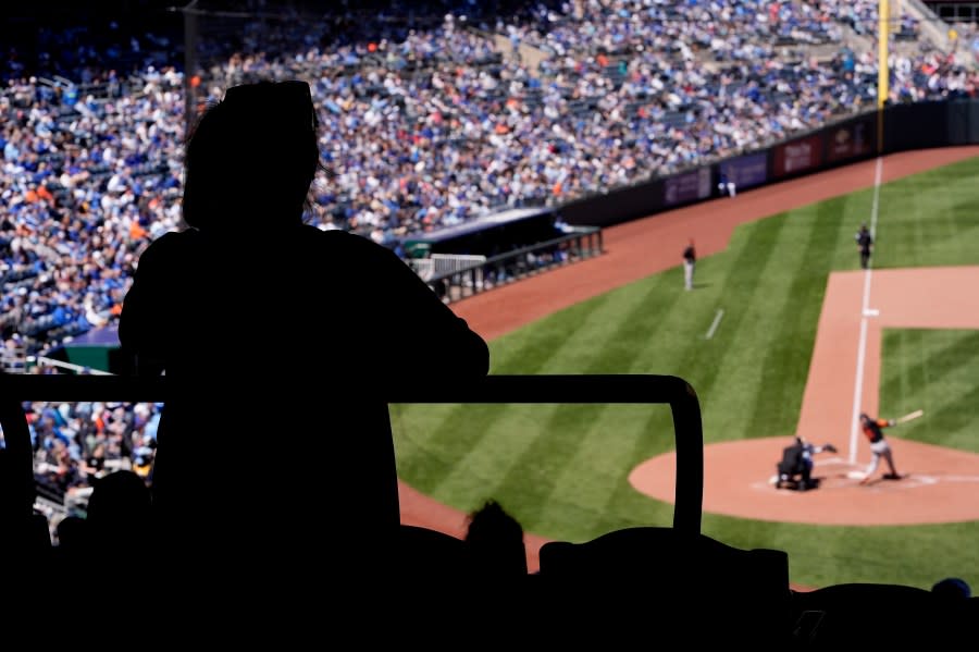 A fan watches from the concourse during the sixth inning of a baseball game between the Kansas City Royals and the Baltimore Orioles Sunday, April 21, 2024, in Kansas City, Mo. (AP Photo/Charlie Riedel)