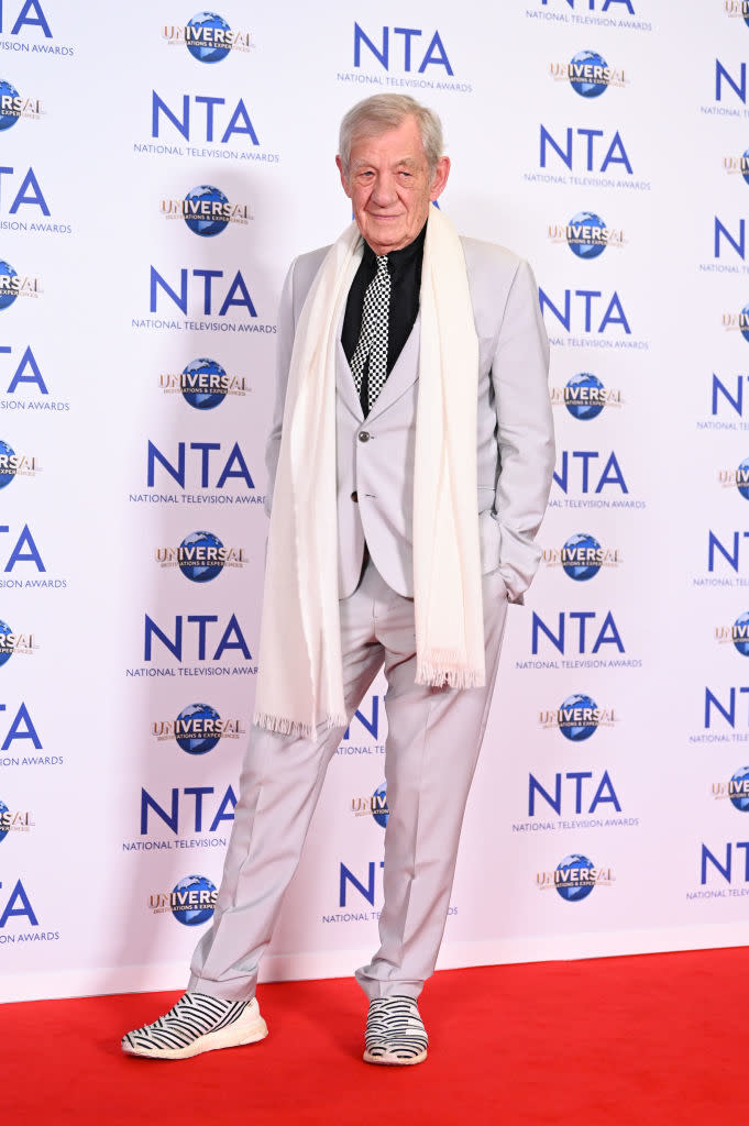 Ian McKellen in a light suit with a striped scarf and black-and-white sneakers at the NTA event