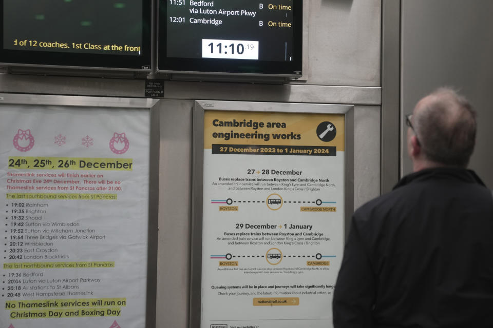 A traveller walks past a notice giving travel details for the upcoming Christmas holiday period at King's Cross station in London, Thursday, Dec. 21, 2023. Rail travellers over the Christmas holiday season will have to contend with disruptions to services due to engineering work and bad weather. (AP Photo/Kin Cheung)