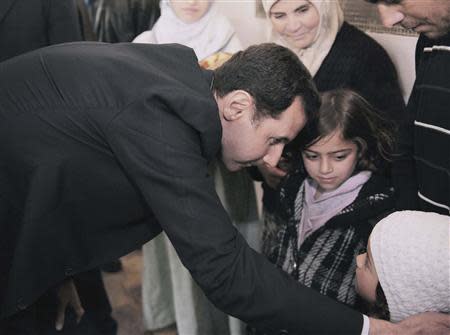 Syria's President Bashar al-Assad speaks with children during his visit to displaced Syrians in the town of Adra in the Damascus countryside March 12, 2014, in this handout photograph released by Syria's national news agency SANA. REUTERS/SANA/Handout via Reuters