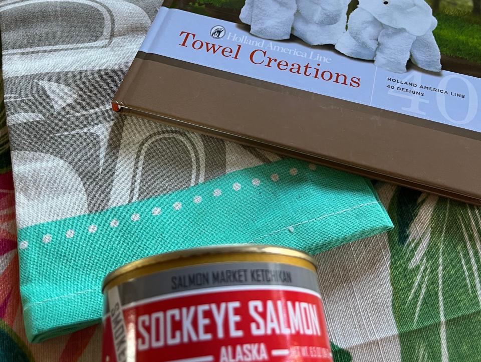 souvenirs from an alaskan cruise, including towel folding book and tinned salmon