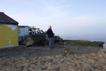 Bryony Nierop-Reading, a 69-year-old pensioner, stands by the remains of her bungalow that was demolished by the local Happisburgh council after a winter storm eroded the coastline and left it perched over the edge of a cliff, March 12, 2014. REUTERS/Alister Doyle