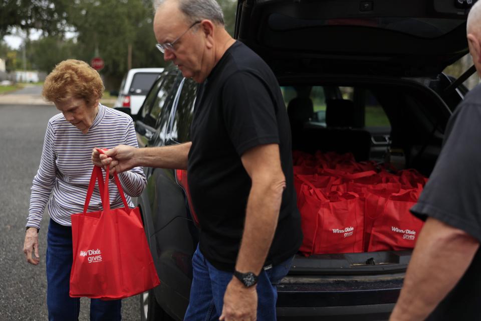 Mary Alice Wolfe and former third-grade student Chris Stanton prepare to deliver food, including red-bagged Thanksgiving meal fixings donated by Winn-Dixie, to needy seniors in Hastings in St. Johns County.