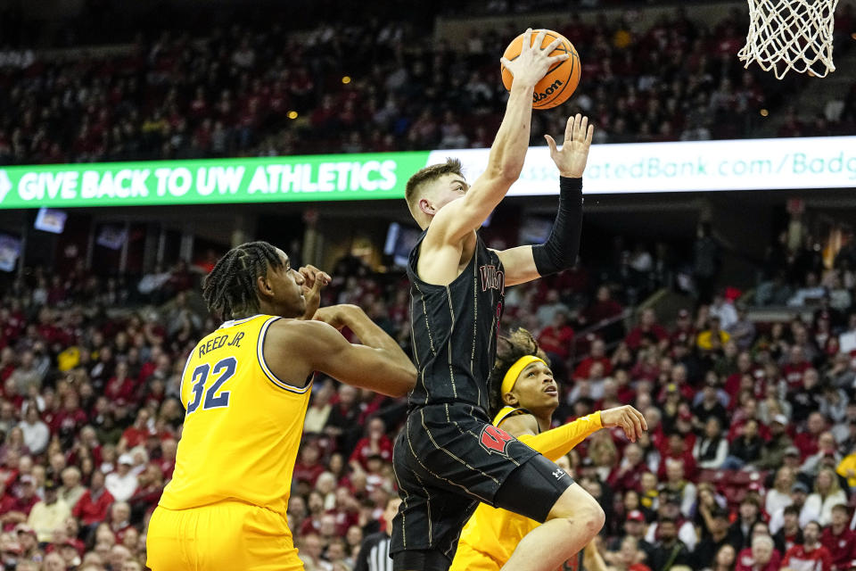 Wisconsin's Connor Essegian (3) shoots past Michigan's Tarris Reed (32) and Dug McDaniel, right, during the second half of an NCAA college basketball game Tuesday, Feb. 14, 2023, in Madison, Wis. (AP Photo/Andy Manis)