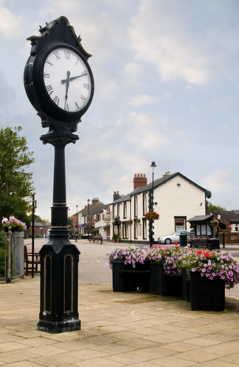 Freckleton Village and clock in Lancashire, with flower display and public house