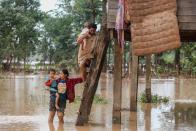 <p>A couple carry their children from their home in the flooded area in Sanamxai, Attapeu province, on July 26, 2018. (Photo: Kao Nguyen/AFP/Getty Images) </p>