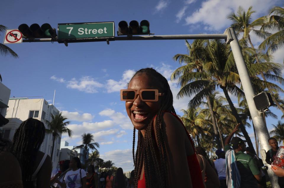 Spring break tourists walk Ocean Drive several hours prior to a city-wide curfew that was put into effect after several nights of mass arrests, Sunday, March 21, 2021, in Miami Beach, Fla. An 8 p.m. curfew has been extended in Miami Beach after law enforcement worked to contain unruly crowds of spring break tourists. (Carl Juste/Miami Herald via AP)