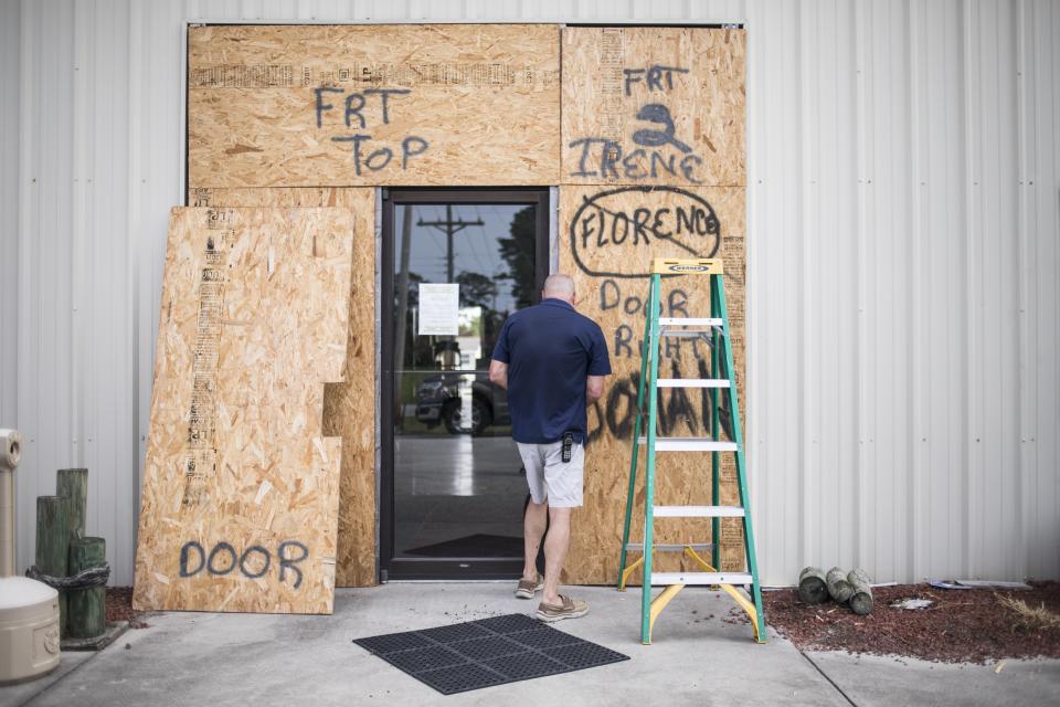 Terry Crabtree termina de colocar tablas de madera para proteger la entrada al Downeast Marine, en Otway, Carolina del Norte, ante la cercanía del huracán Isaías, el 3 de agosto de 2020. (Julia Wall/The News & Observer via AP)