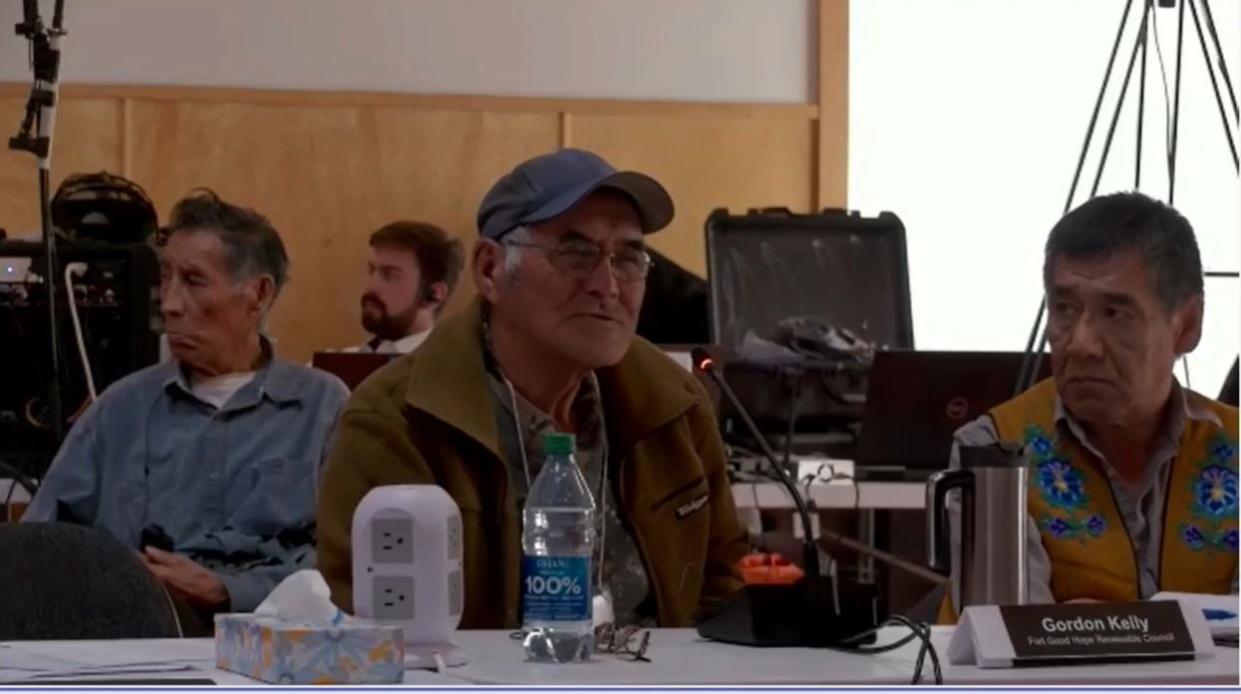 Edwin Erutze (right) watches Fort Good Hope, N.W.T. elder Gordon Kelly present at a Canada Energy Regulator oral Indigenous knowledge hearing in the community on May 15, 2024. (Canada Energy Regulator - image credit)