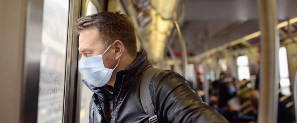 Mature man wearing disposable medical face mask in car of the subway in New York during coronavirus outbreak. Safety in a public place while epidemic of covid-19.