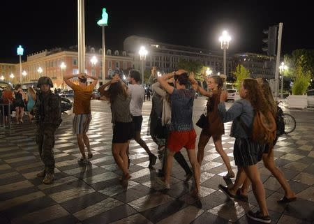 People cross the street with their hands on thier heads as a French soldier secures the area July 15, 2016 after at least 60 people were killed along the Promenade des Anglais in Nice, France, when a truck ran into a crowd celebrating the Bastille Day national holiday July 14. REUTERS/Jean-Pierre Amet