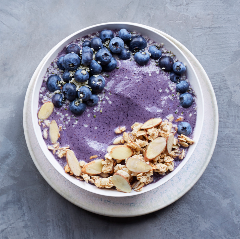 blueberry smoothie bowl topped with blueberries, granola and sliced almonds