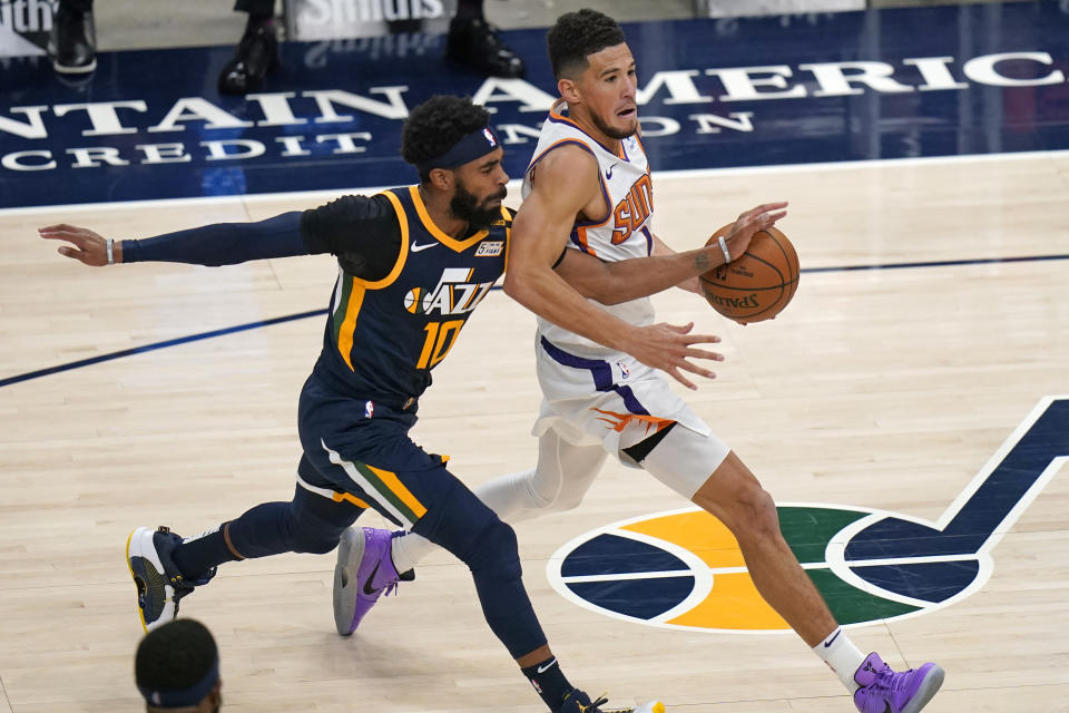 Phoenix Suns guard Devin Booker drives to the basket as Utah Jazz guard Mike Conley (10) defends during the second half of an NBA basketball game Thursday, Dec. 31, 2020, in Salt Lake City. (AP Photo/Rick Bowmer)