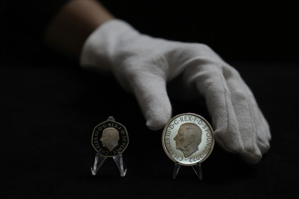 Two new coins bearing official coinage portrait of King Charles III, on the left is the new 50 pence coin, and right is the new 5 pound commemorative coin, which will be among the first coins to bear the new king's head, during a press preview in London, Thursday, Sept. 29, 2022. The likeness of the king was created by British sculptor Martin Jennings, and approved by the king. (AP Photo/Alastair Grant)