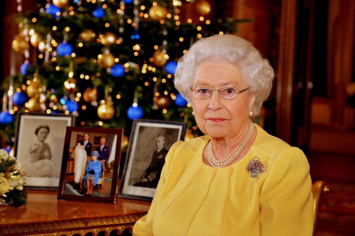 LONDON, UNITED KINGDOM - DECEMBER 12: Queen Elizabeth II records her Christmas message to the Commonwealth, in the Blue Drawing Room at Buckingham Palace on December 12, 2013 in London England. Broadcast on December 25, 2013, the Queen wears a diamond, ruby and sapphire brooch given to her by her parents to celebrate the birth of Prince Charles in 1948. By her side are photographs of her parents, King George VI and Queen Elizabeth - The Queen Mother, and also a picture from this years christening of Prince George of Cambridge. (Photo by John Stillwell - WPA Pool/Getty Images)