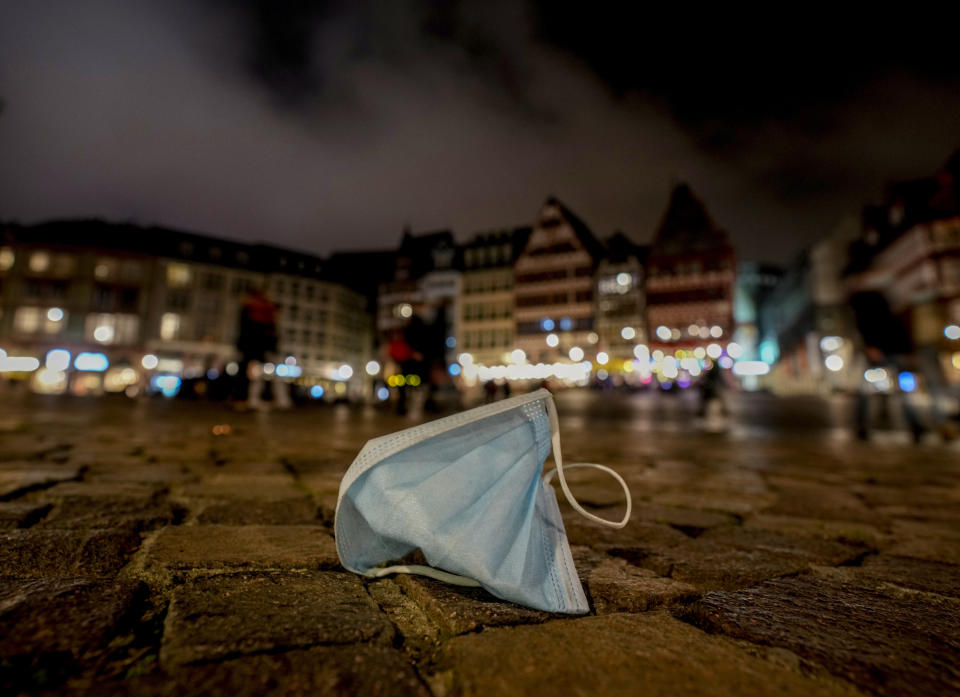 FILE - A face mask left on Roemerberg square in Frankfurt, Germany, Nov. 6, 2021. The pandemic is again roaring across parts of Western Europe, a prosperous region with relatively high vaccination rates and good health care systems but where lockdown measures to rein in the virus are largely a thing of the past. “Germany, along with parts of France and areas of Eastern Europe, is a good example of what happens when you have widespread reluctance to vaccination. Now those segments of the population at the highest risk are paying the price,” Rafael Bengoa, former Director for Health Systems at the World Health Organization and one of Spain’s leading public health experts, told Spanish public broadcaster TVE. (AP Photo/Michael Probst, file)