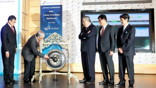 Chairman of IHH Healthcare Abu Bakar Suleiman (2nd, L) hits a gong to mark the company's listing debut at Malaysia Stock Exchange in Kuala Lumpur on July 25, 2012