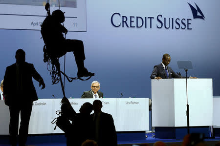 Chairman Urs Rohner (L) and CEO Tidjane Thiam of Swiss bank Credit Suisse are seen in the back as an activist of environmental group Greenpeace abseils after unveiling a banner to protest against the financing of the Dakota-Access oil pipeline during the bank's annual shareholder meeting in Zurich, Switzerland April 28, 2017. REUTERS/Arnd Wiegmann