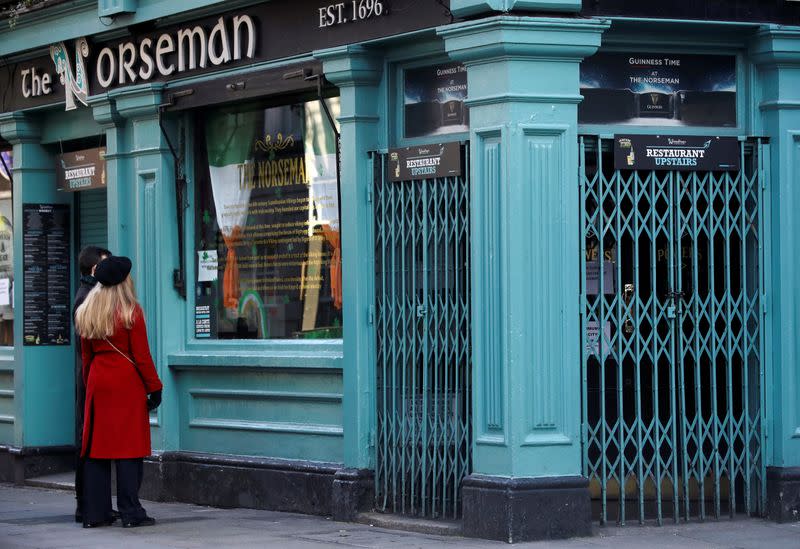 Two people read the closure notice in the window of The Norseman pub, as bars across Ireland are to close voluntarily to curb the spread of coronavirus in Dublin