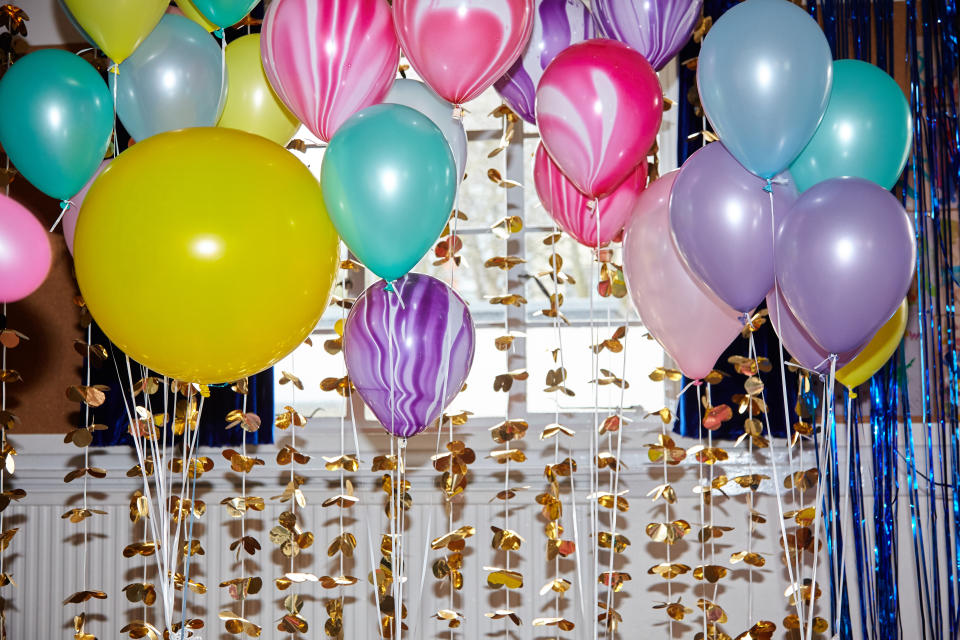 A group of multi coloured helium balloons at a birthday celebration