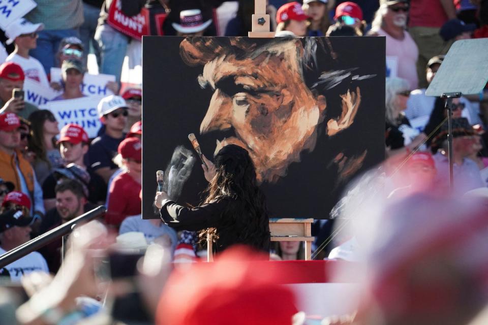 An artist paints a portrait of former Trump before his appearance on stage at Waco (REUTERS)