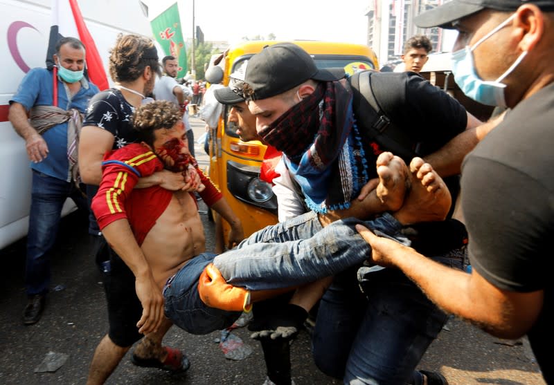 Demonstrators carry an injured man during a protest over corruption, lack of jobs, and poor services, in Baghdad