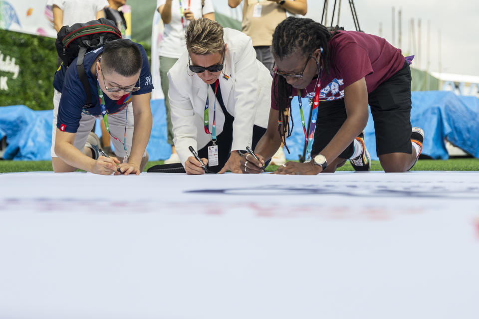 Participants sign on the quilt at the AIDS Quilt Memorial Ceremony, ahead of the Gay Games in Hong Kong, Saturday, Nov. 4, 2023. The first Gay Games in Asia are fostering hopes for wider LGBTQ+ inclusion in the regional financial hub, following recent court wins in favor of equality for same-sex couples and transgender people. (AP Photo/Chan Long Hei)