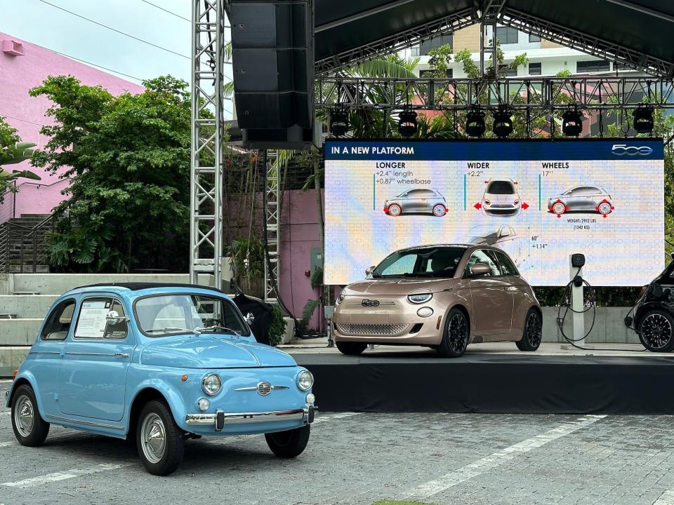 older blue fiat in front of a new golden brown fiat on a stage