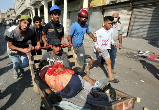 Iraqi demonstrators evacuate a man wounded in clashes with security forces on Baghdad's Martyrs' Bridge (Jisr Al-Shuhada)