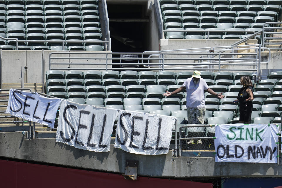 Fans stand in seats above signs calling for Oakland Athletics management to sell the team during the first inning of a baseball game between the Athletics and the Texas Rangers in Oakland, Calif., Saturday, May 13, 2023. (AP Photo/Jeff Chiu)
