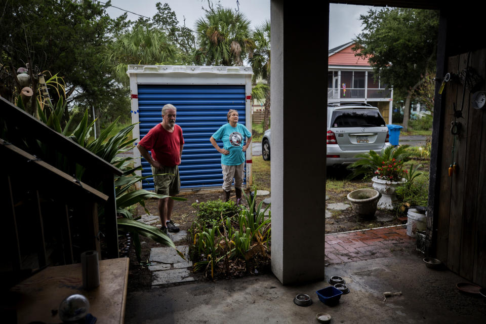 Sandy Cason, center, and her husband David Cason, left, stand outside their home before evacuating as Hurricane Dorian makes its way up the east coast, Wednesday, Sept. 4, 2019, in Tybee Island, Ga. The Casons are still repairing damage from the two previous storms that came close to the coastal barrier island. Sandy Cason said she's not ready to blame climate change. She noted records show Georgia got hit by several powerful hurricanes in the 1800s. (AP Photo/Stephen B. Morton)
