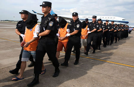 Chinese police officers escort a group of Chinese nationals suspected of telecom fraud after they were deported from Cambodia, at Changsha Huanghua International Airport in Changsha, Hunan province, China July 6, 2017. China Daily via REUTERS