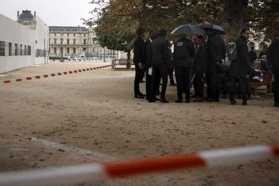 Empleados esperan después de la evacuación del Museo de Louvre en París, el sábado 14 de octubre de 2023. (AP Foto/Thomas Padilla)