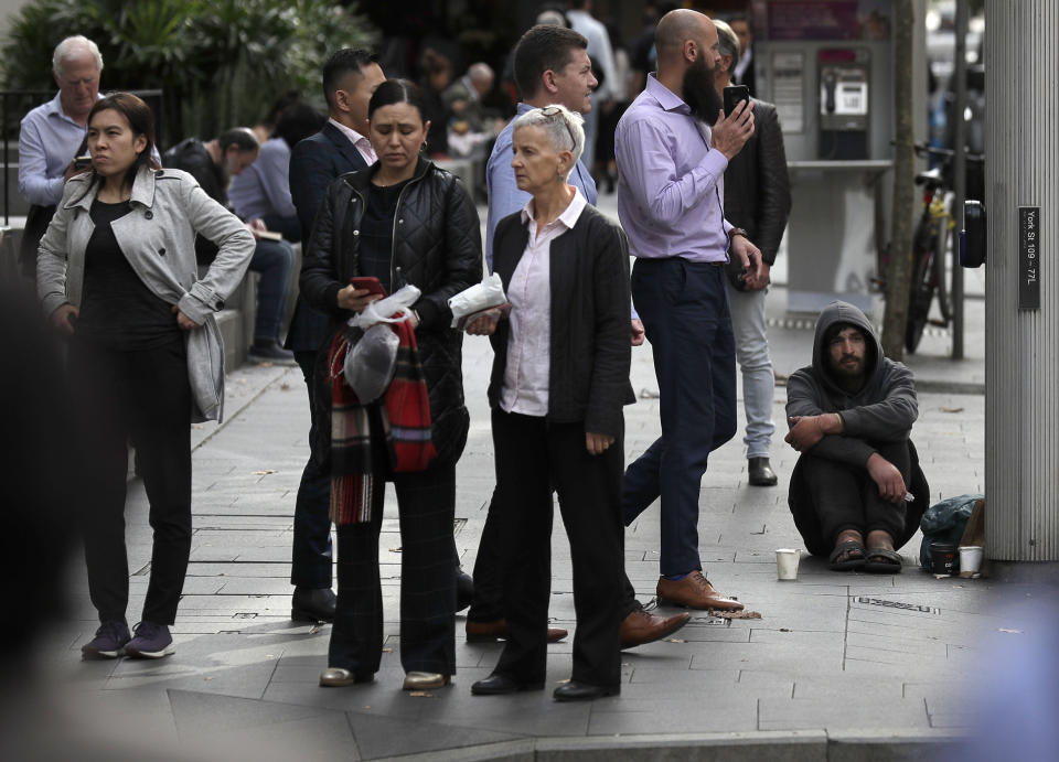 A man, at right, panhandles for money on a corner in Sydney, Tuesday, May 11, 2021, as the government prepares to release its big-spending economic plan for the next fiscal year designed to create jobs and repair pandemic damage and with an eye toward winning votes at looming general elections. Treasurer Josh Frydenberg said the economy was already recovering from the pandemic and his economic blueprint for the fiscal year starting on July 1 would create more economic strength. (AP Photo/Rick Rycroft)