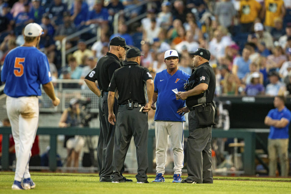 Florida head coach Kevin O'Sullivan is instructed to change pitchers for too many visits to the mound during the eighth inning against Oral Roberts in a baseball game at the NCAA College World Series in Omaha, Neb., Sunday, June 18, 2023. (AP Photo/John Peterson)