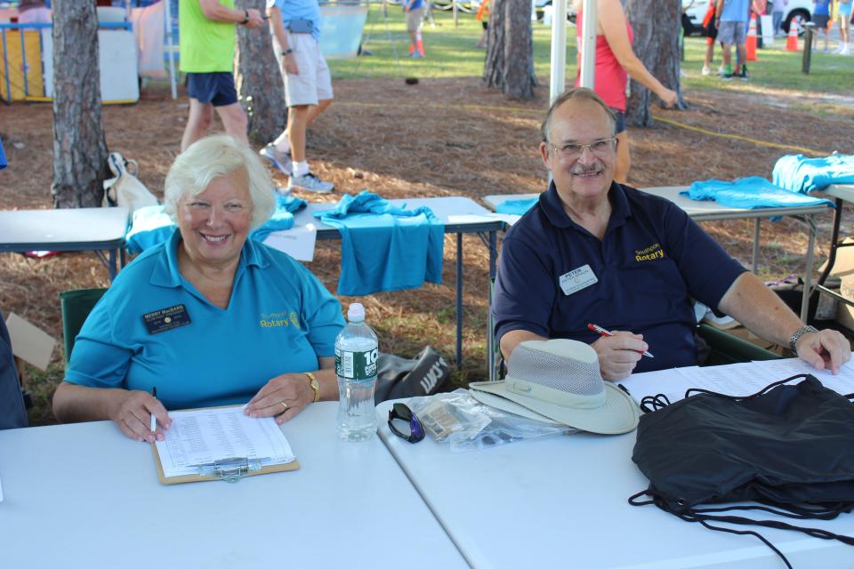 Merry McBarb and Peter Braun volunteer with the Southport Rotary Club during the Go Jump in the Lake 5K race on Monday, Sept. 4.