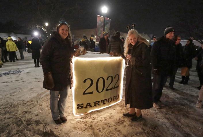 Two women stand near the big cheese following the Plymouth Arts Center - Big Cheese Drop In Plymouth One Of The Quirkiest New Year’s Eve Traditions In The US. Plus, More Sheboygan County News In Weekly Dose.'s 15th annual Sartori Big Cheese Drop Dec. 31, 2021, in Plymouth, Wisconsin.