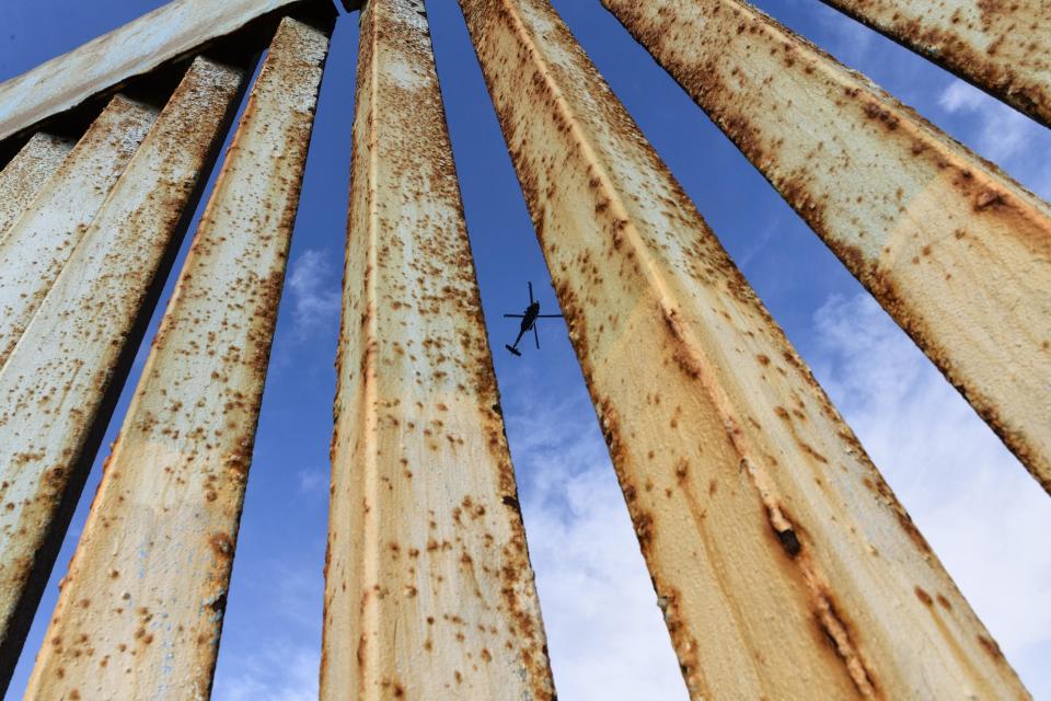 FILE - In this Dec. 23, 2018, file photo, a helicopter monitors the U.S. border fence from above, seen from Tijuana, Mexico. (AP Photo/Daniel Ochoa de Olza, File)