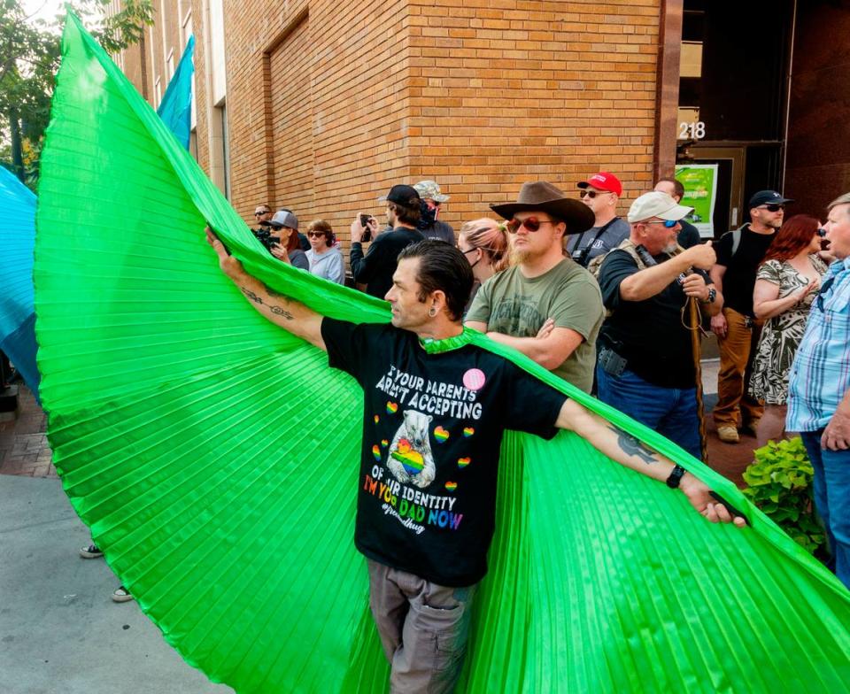 A man who goes by Je uses large green wings to put a wall between a small group of protesters standing outside the entrance of the Boise Pride Festival on Sunday, Sept. 11, 2022. The annual event faced backlash from some community members asking sponsors of the three-day event to pull their funding because a children’s drag show performance was on the schedule.