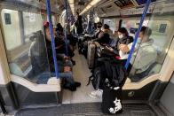 People mainly wearing face coverings sit on the Tube towards Heathrow Airport in London, Monday, Nov. 29, 2021. The new potentially more contagious omicron variant of the coronavirus popped up in more European countries on Saturday, just days after being identified in South Africa, leaving governments around the world scrambling to stop the spread. In Britain, Prime Minister Boris Johnson said mask-wearing in shops and on public transport will be required, starting Tuesday. (AP Photo/Frank Augstein)