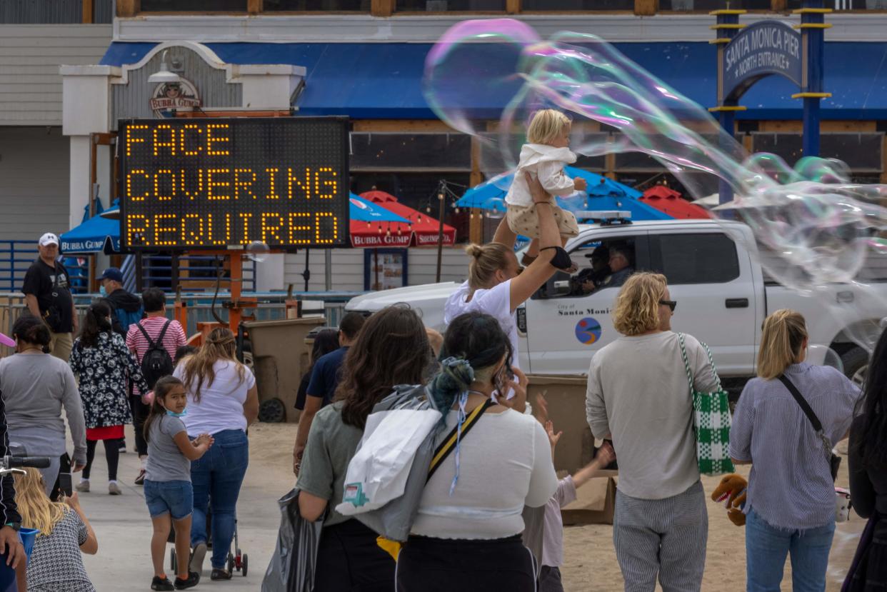 People walk past bubbles near the Santa Monica Pier as crowds gather on Memorial Day as shutdowns are relaxed more than a year after Covid-19 pandemic shutdowns began, in Santa Monica, California on May 31, 2021. (Photo by DAVID MCNEW / AFP) (Photo by DAVID MCNEW/AFP via Getty Images)