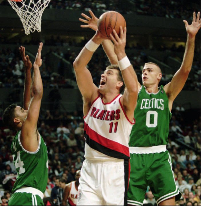 Portland Trail Blazers center Arvydas Sabonis (11) attempts to put up a shot over the defensive pressure of Boston Celtics center Eric Montross (0) and forward Rick Fox during their last preseason game in Portland, Ore., Oct. 24, 1995. The 7-foot-3, 300-pound center, long considered to be the best player in Europe, says he already has noticed a difference in how the game is played in the NBA. (AP Photo/Shane Young)