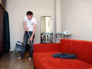 Man mopping the floor of a messy house