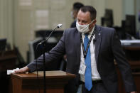 FILE — In this Monday June 15, 2020 file photo an Assembly Sargent-at-Arms wears a face mask as he disinfects the podium between use by Assembly members at the Capitol in Sacramento, Calif. California will require state employees and all health care workers to show proof of COVID-19 vaccination or get tested weekly in an effort to slow the rising coronavirus infections, mostly among the unvaccinated. The new rule will take effect next month. (AP Photo/Rich Pedroncelli, File)