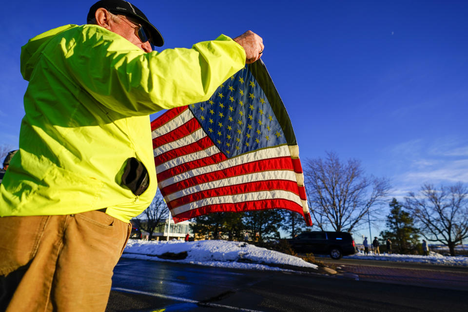 A supporter waves an American flag as President Joe Biden's motorcade passes by during his tour of the Marshall Fire destruction Friday, Jan. 7, 2022, in Louisville, Colo. (AP Photo/Jack Dempsey)