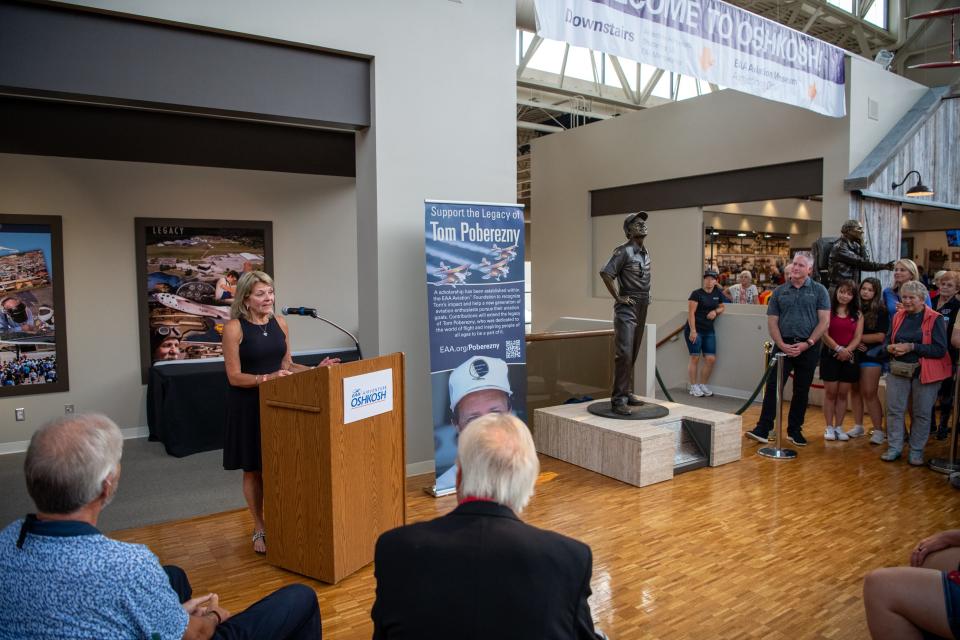 Sharon Poberezny, at lectern, speaks at the unveiling of a full-size bronze sculpture of her late husband, longtime EAA President Tom Poberezny, at the EAA Aviation Museum July 24, 2023, in Oshkosh.