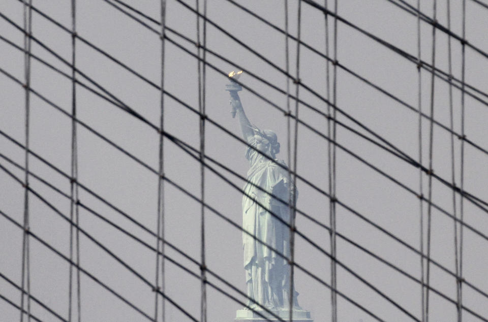 FILE - In this May 1, 2010 file photo, the Statue of Liberty appears through support cables on the Brooklyn Bridge in New York. The Statue of Liberty, which has been closed to visitors since Superstorm Sandy, is scheduled to reopen for tours July Fourth, when Statue Cruises resumes departures for Liberty Island from Lower Manhattan. For tourists who want a photo of the famous statue without visiting the island, there are many options and vantage points, including a view from a walk over the Brooklyn Bridge. (AP Photo/Peter Morgan, file)