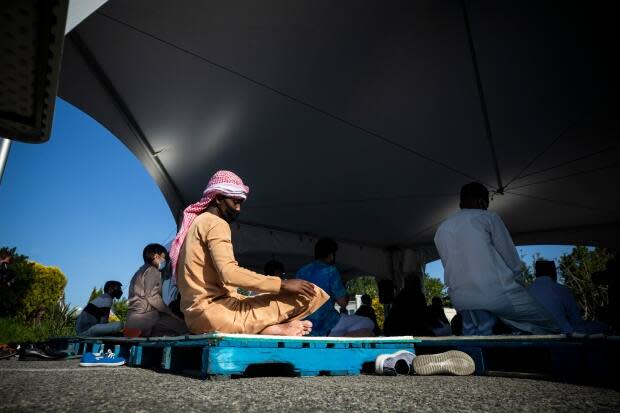 Gorad Ali prays outdoors, six-feet apart from other members of the Muslim community, outside the Richmond Jamea Masjid Thursday.