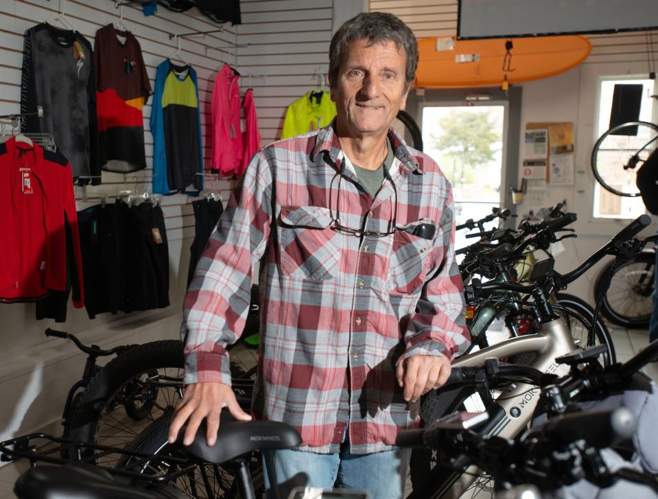 Jim Ballantyne at the Buzzards Bay Bikes shop is surrounded by a variety of e-bike models.