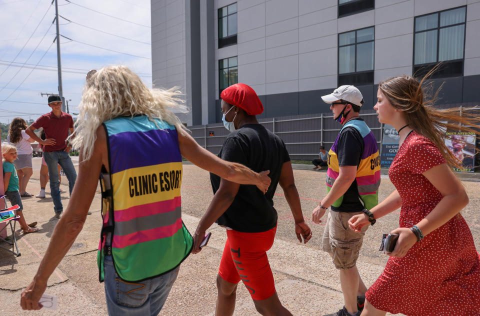 Derenda Hancock, who leads the Pink House Defenders, a group of volunteer abortion clinic escorts at the Jackson Women's Health Organization, ushers a woman surrounded by anti-abortion protestors, into the clinic in Jackson, Miss., on May 22, 2021 (Evelyn Hockstein / Reuters via Alamy Stock Photo)